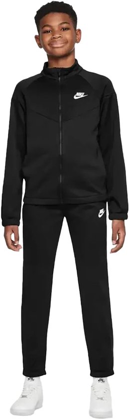 Jongen in zwart Nike trainingspak met wit T-shirt en witte sneakers.