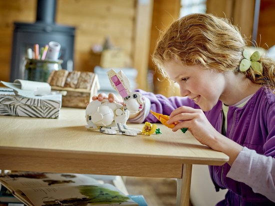 Une fille nourrit un lapin LEGO blanc avec une carotte.
