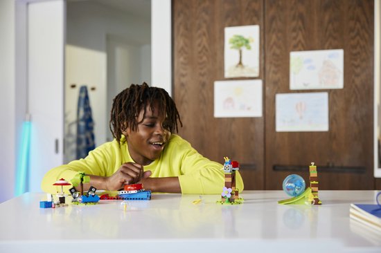 Een jongen met een gele trui die met een LEGO Sonic speelset speelt, met Sonic op een platform met speakers.