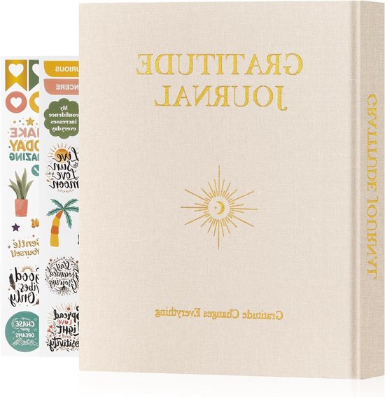 Een crèmekleurig dankbaarheidsdagboek met gouden belettering en een zon-maanicoon. Een vel met kleurrijke stickers ligt ernaast.