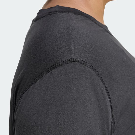 Detailopname van de schouder en neknaad van een donkergrijs Adidas performance T-shirt.