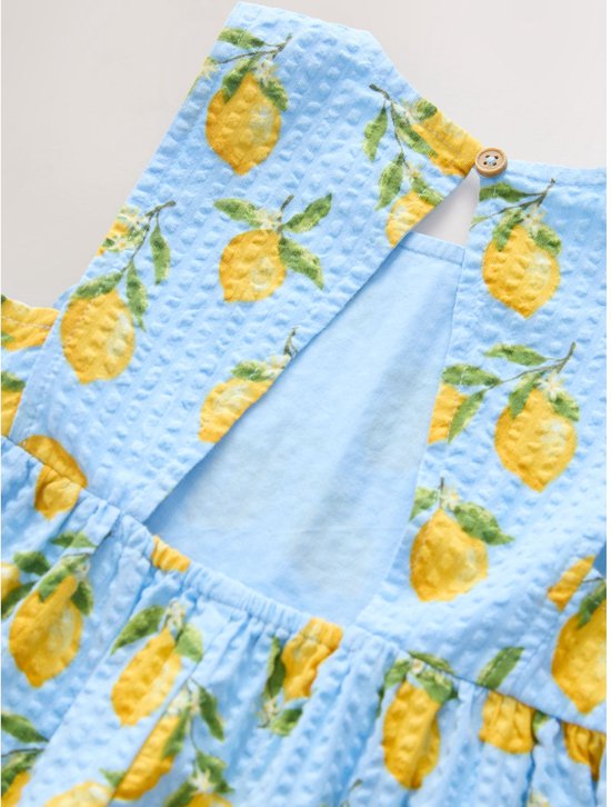 Sluiting van de lichtblauwe playsuit met citroenprint: knoopje in de nek en rug-uitsnijding.