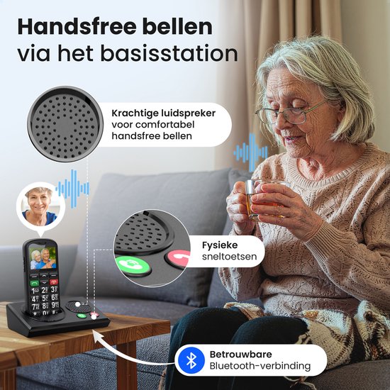 Oudere vrouw met een seniorentelefoon op het oplaadstation. Handsfree bellen via de luidspreker.