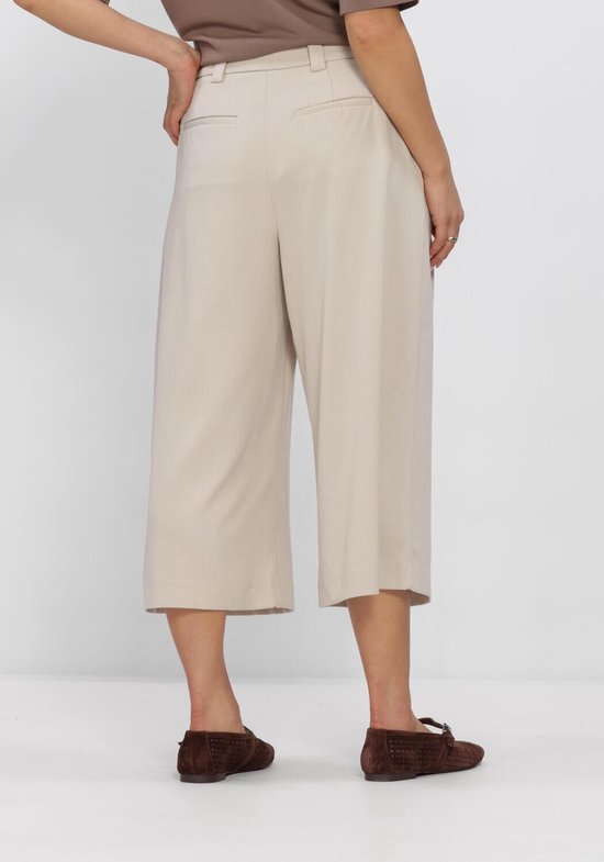 Achterkant van een beige culotte broek met plooien, tot halverwege de kuit.