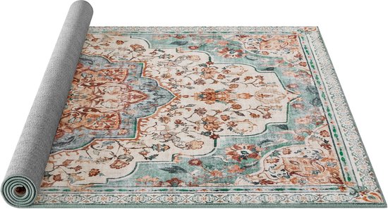 Tapis sur fond crème, orné de fleurs rouille, orange et vertes, avec un médaillon central. Un coin est enroulé.