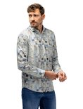 Man met donker haar, baard en snor, draagt een blauw-bruin blokkerig overhemd en spijkerbroek, mouwen oprollend.