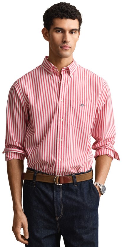 Man, rood en wit gestreept button-down overhemd met borstzakje, denim jeans, bruine riem.