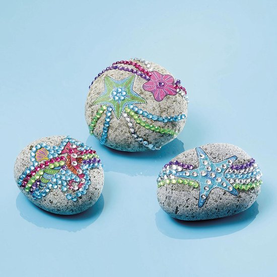 Drie grijze stenen versierd met gekleurde strass steentjes, zeesterren, bloemen en zeepaardje.