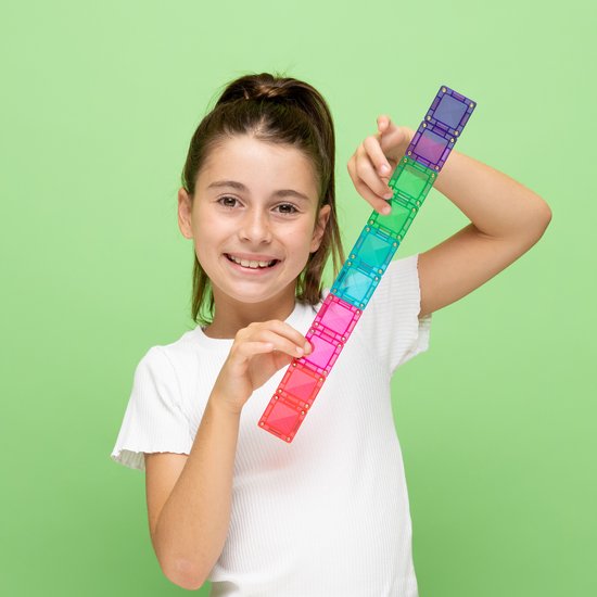 Meisje houdt een regenboog-staf vast, gemaakt van Connetix magnetische tegels in rood, roze, cyaan, groen en paars.