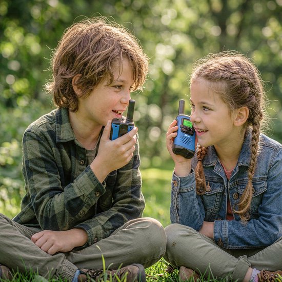 Jongen en meisje met walkietalkies in een bosrijke omgeving.