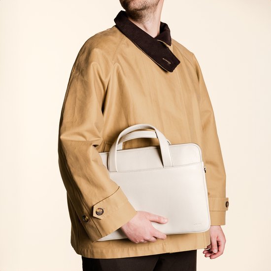 Man met beige jas en bruine broek draagt een off-white laptoptas.