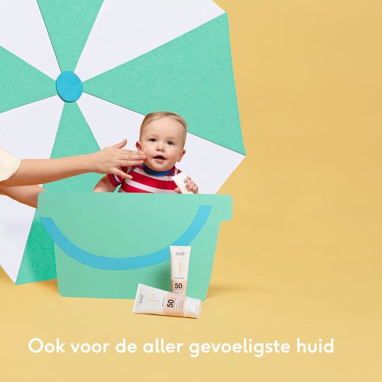 Baby met zonnebrandcrème op gezicht, naast twee tubes Naïf Baby & Kids SPF 50, in een strandemmer.
