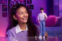 Meisje met krullend haar kijkt naar Jinu pop met roze zonnebril, geruit overhemd en gescheurde jeans.