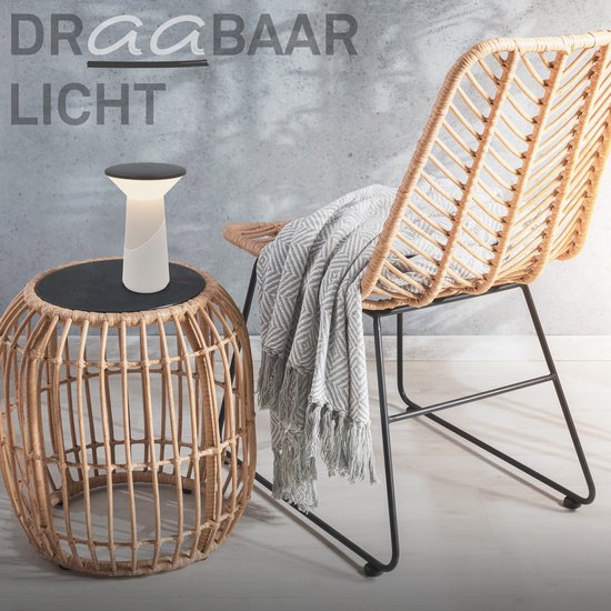 Pilia draagbare lamp op een rieten bijzettafel naast een rieten stoel met een deken. Tekst: DRAAGBAAR LICHT.