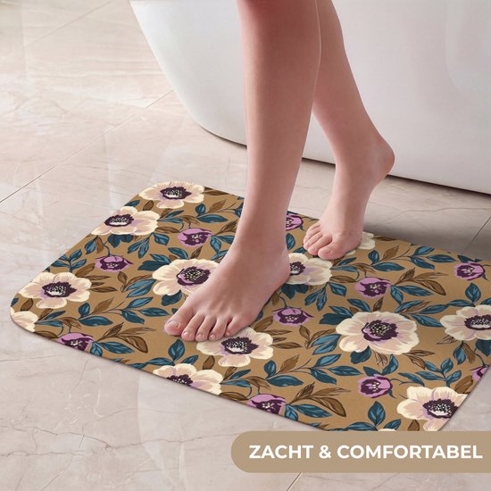 Blote voeten op een zachte, comfortabele badmat met een bruine achtergrond en een patroon van witte, paarse en blauwe bloemen en bladeren.