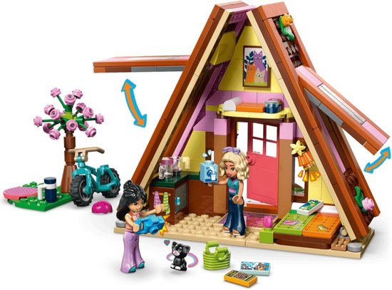 Lego Friends speelgoedhuisje met roze accenten, fiets en poppetjes. Twee poppetjes, katje en plantenbak bij het huisje.