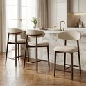 Drie beige barkrukken met houten poten en rugleuning bij een keukenbar.