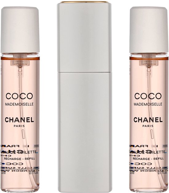 Drie flacons Coco Mademoiselle Eau de Toilette van Chanel, waarvan twee navulbaar, naast een zilverkleurige verstuiver.