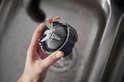 Hand wast een blenderopzetstuk met messen onder een kraan.