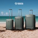 Drie groene Princess Traveller koffers van verschillende formaten op een strand.