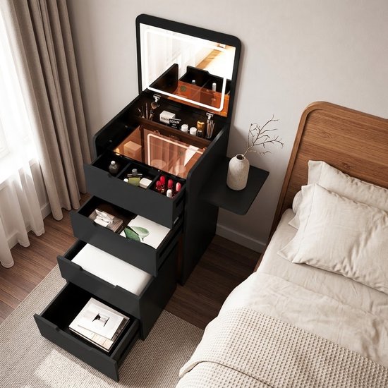 Zwarte kaptafel met geopende laden, spiegel met LED-verlichting, make-up organizers, naast een bed met houten hoofdbord.
