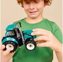 Jongen houdt een felgroene tractor vast met grote zwarte banden en witte velgen.