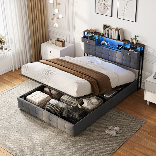 Grijs gestoffeerd 160x200 bed met open opbergruimte onder de matras, hoofdbord met open vakken en laden.