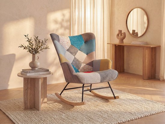Grijze fauteuil met patchwork design in diverse kleuren, in een woonkamer met een bijzettafel.
