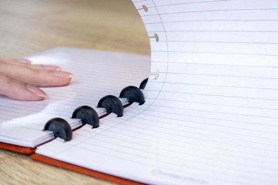 Close-up van een hand die bladzijdes van een Correctbook met een zwarte ringband omslaat.