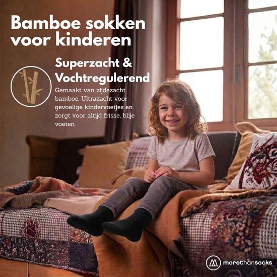 Een lachend meisje zit op een bed met zwarte bamboe sokken aan.