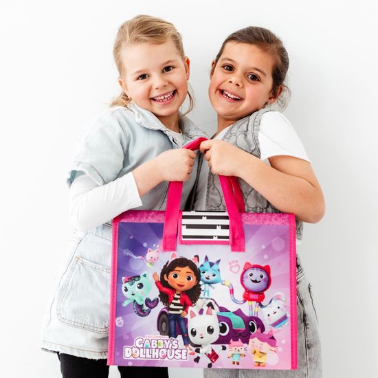 Twee lachende meisjes houden een roze tas vast met Gabby's Poppenhuis personages, waaronder Gabby en haar katten.