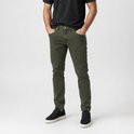 Een man met handen in zakken van een groene corduroy broek, met zwarte sneakers.