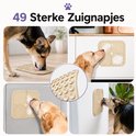 Collage van vier foto's waarop honden likken van een beige likmat die vastzit op verschillende oppervlakken.