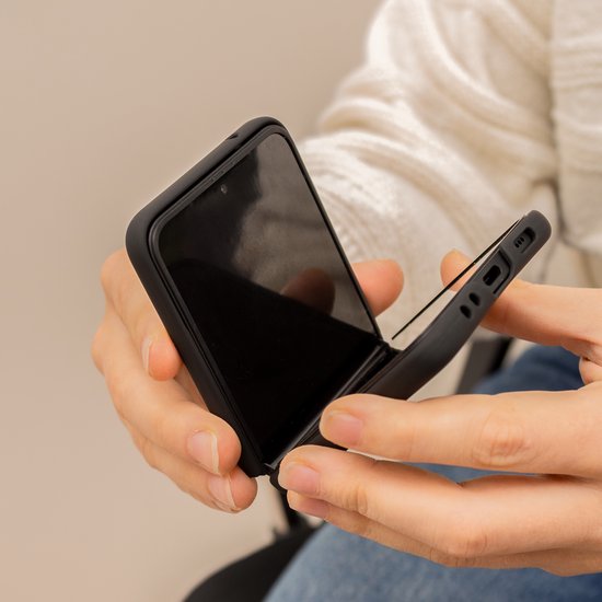 Handen die een open zwarte opklapbare telefoonhoes vasthouden.