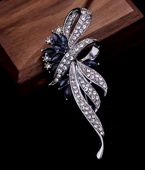 Zilverkleurige broche met blauwe edelstenen en kristallen, in bloemvorm.