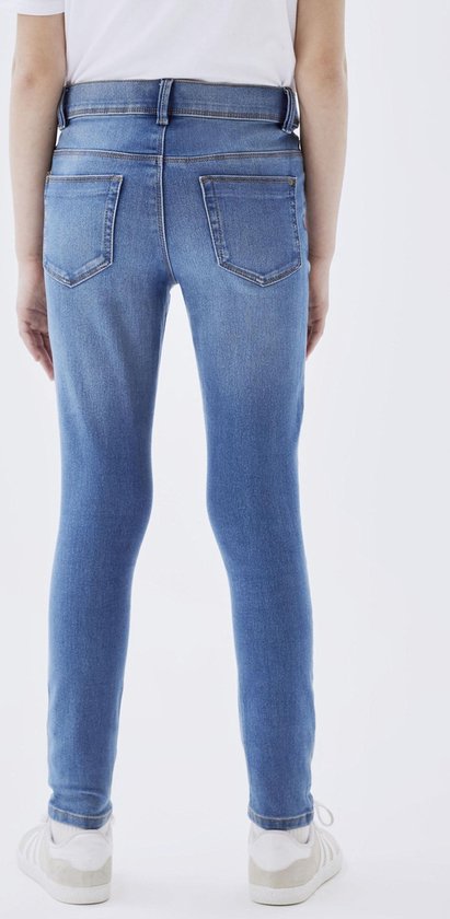 Meisje in een blauwe skinny spijkerbroek, gezien vanaf de achterkant.