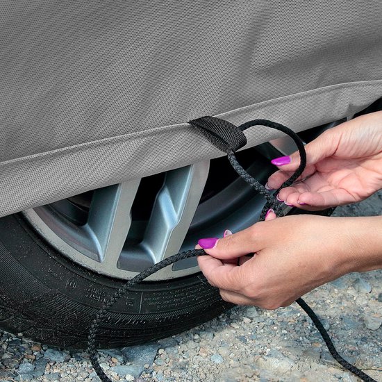 Grijze autohoes met een touwsluiting, vastgehouden door handen met paarse nagellak.