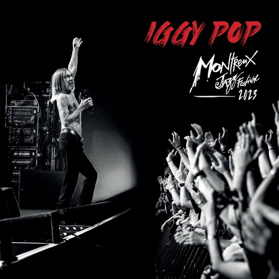 Iggy Pop met zijn arm omhoog op het podium, publiek juicht. Tekst: Iggy Pop Montreux Jazz Festival 2023.