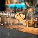 Een cocktailglas gevuld met ijs, partjes citroen en twee zwarte rietjes.