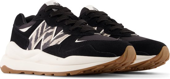 Paar zwarte New Balance sneakers met zebraprint, beige zool en witte veters, van voren gezien.