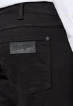 Detail van de achterzak van een zwarte Wrangler jeans met een zwart leren logo.