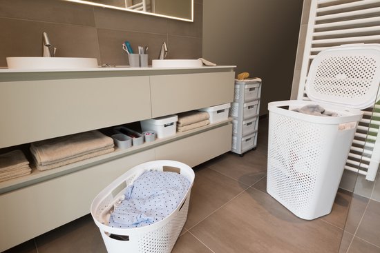 Witte wasmand met deksel in een badkamer, met een andere wasmand ernaast.