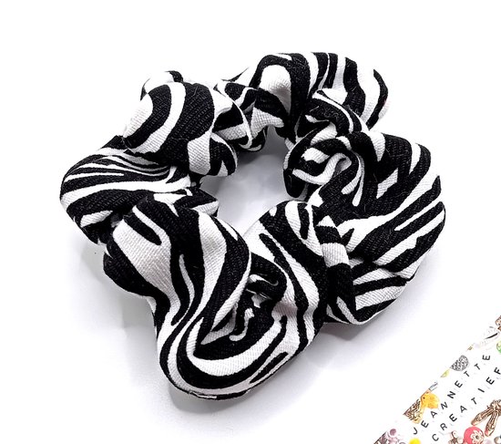 Een scrunchie met een zwart-witte zebraprint, tentoongesteld op een witte achtergrond.
