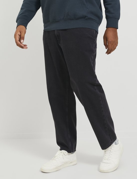 Man in donkergroene hoodie en donkergrijze jeans, close-up van de broek.