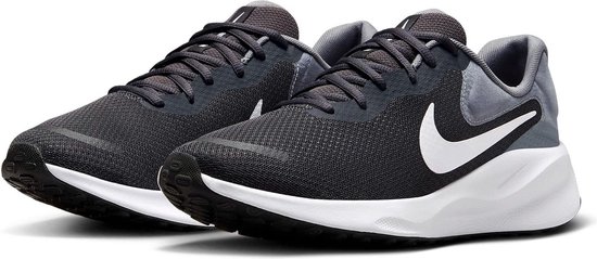Une paire de chaussures de course Nike Revolution gris foncé avec swoosh et semelles blancs.
