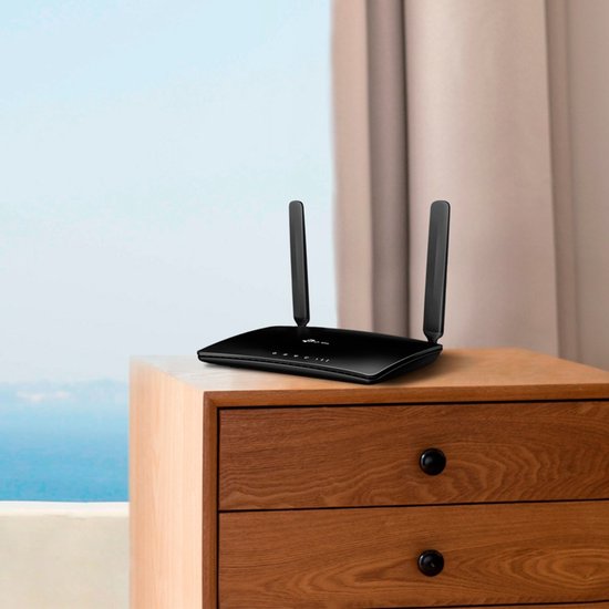 Zwarte TP-Link 4G router met twee antennes op een houten nachtkastje.