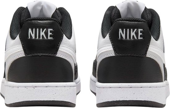 Bovenkant van een paar witte en zwarte Nike Court Vision Low sneakers, met de "NIKE" logo's op de tongen en de hielen.