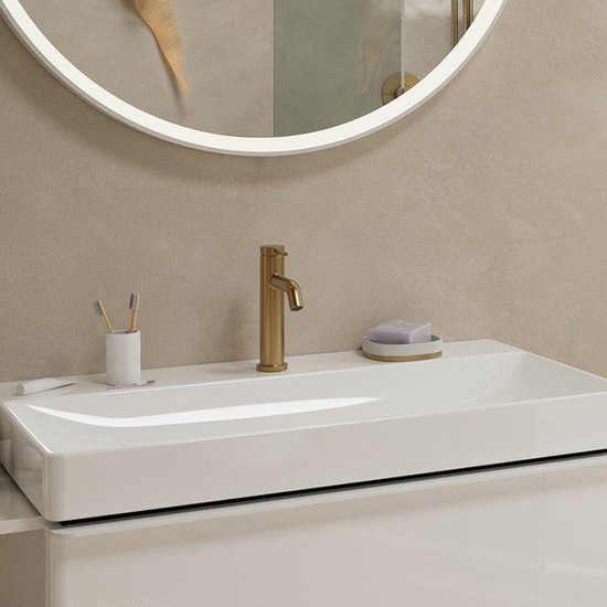Badkamer met witte wastafel, gouden kraan en spiegel met verlichting.