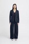 Een vrouw met lang donker haar draagt een marineblauwe blazer met een zwarte top en wijde, marineblauwe broek.