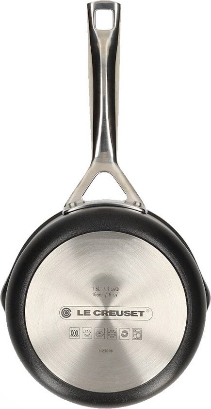 Onderkant van een zwarte steelpan met metalen bodem waarop 'Le Creuset' staat.